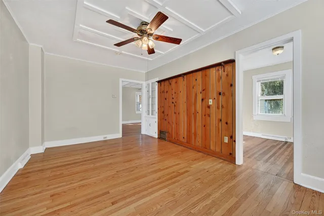 an empty room with wooden floor chandelier fan and windows