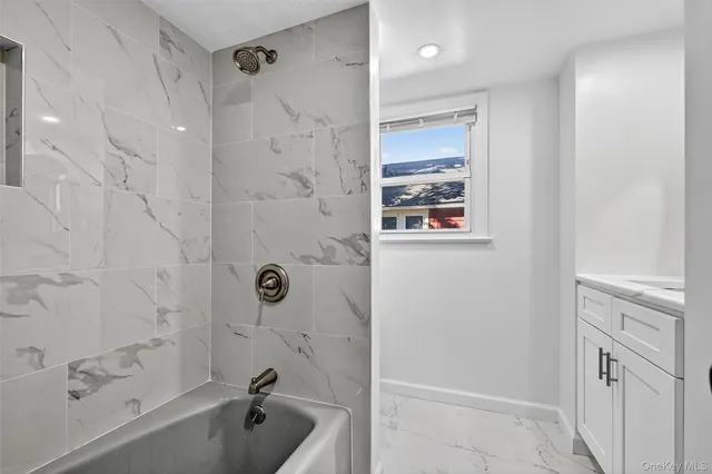 a bathroom with a tub shower vanity and a sink