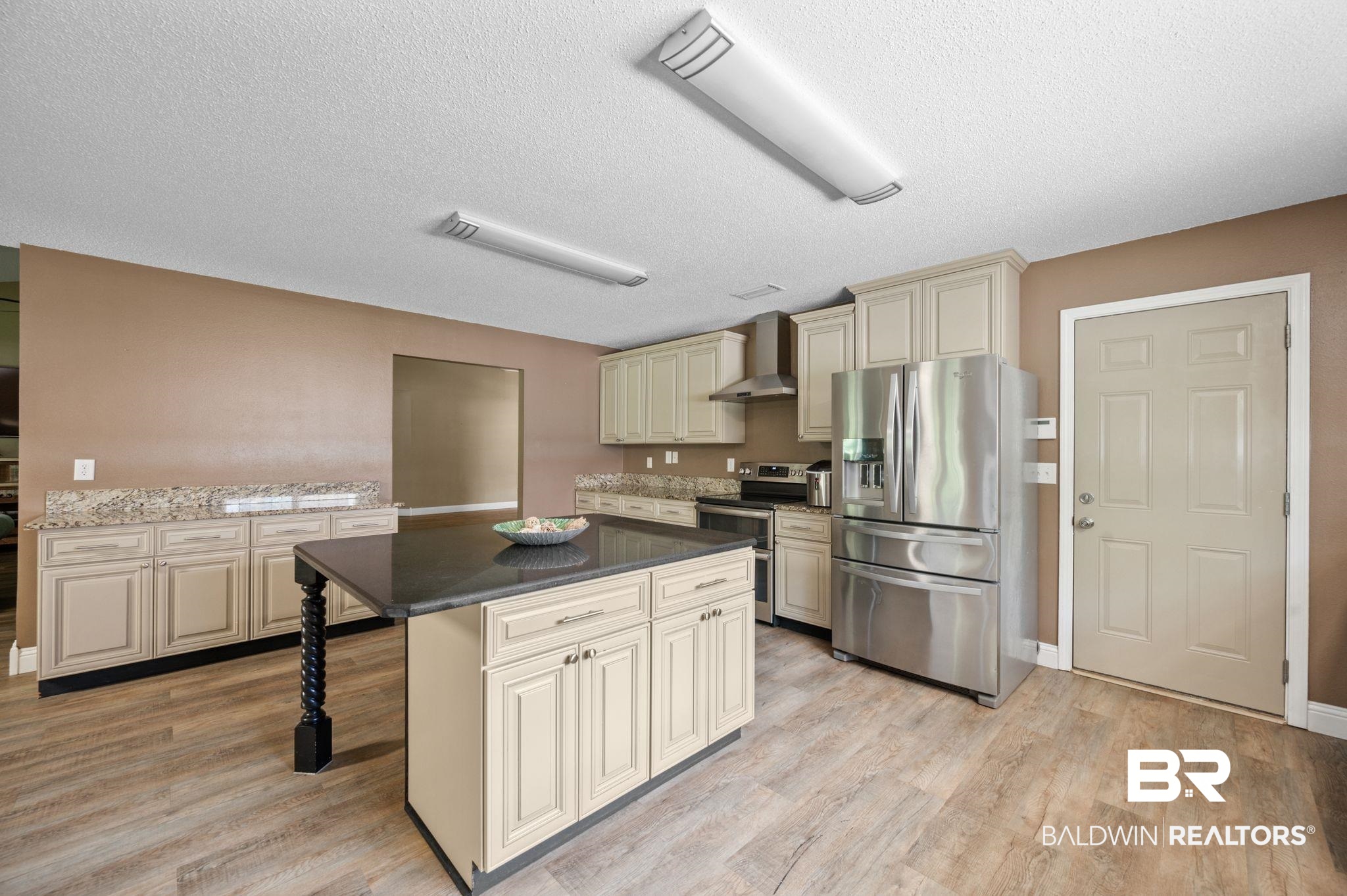 11705 Venice Boulevard Foley, AL 36535 - Photo 9 of 43 Kitchen with cream cabinets, stainless steel appliances, a center island, wall chimney exhaust hood, and light wood-type flooring