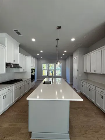 a large kitchen with kitchen island a stove a sink a center island and stainless steel appliances