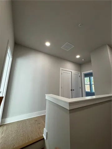 a view of a hallway to room with wooden floor