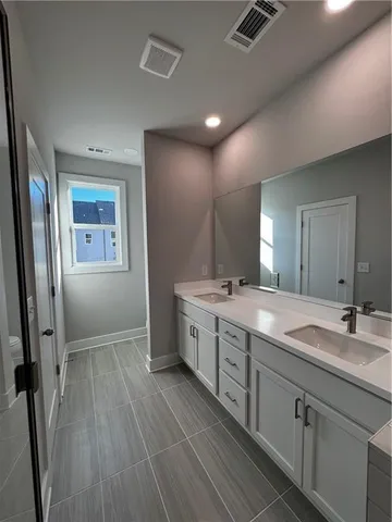 a spacious bathroom with a double vanity sink a large mirror and shower