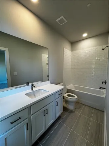 a bathroom with a granite countertop toilet a sink and a bathtub