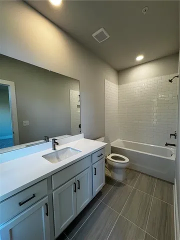 a bathroom with a granite countertop sink a toilet and bathtub