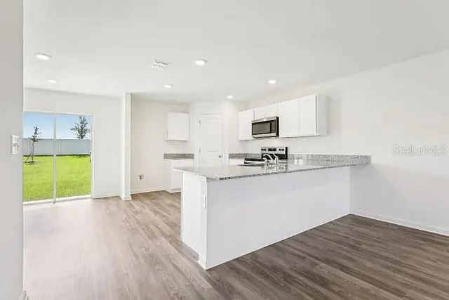 a kitchen with kitchen island granite countertop a sink cabinets and wooden floor