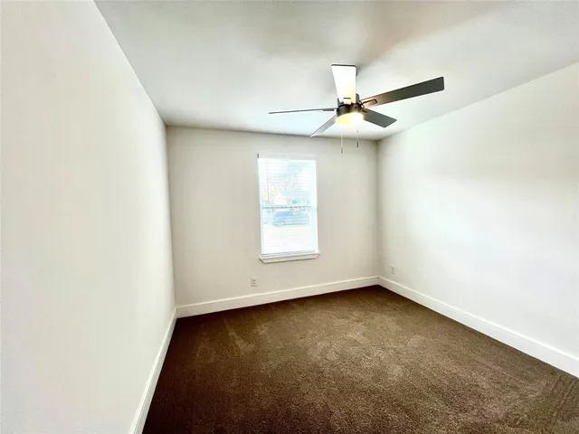 an empty room with a window and a ceiling fan