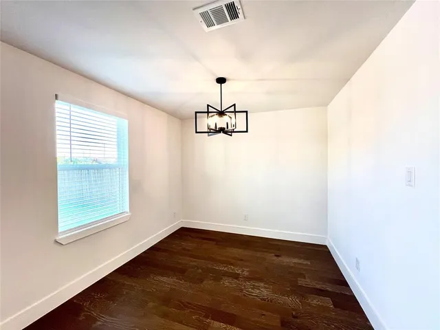 an empty room with wooden floor ceiling fan and window