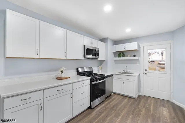 a kitchen with cabinets stainless steel appliances a sink and wooden floor