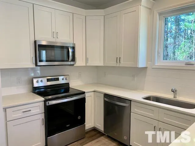 a kitchen with white cabinets and black appliances