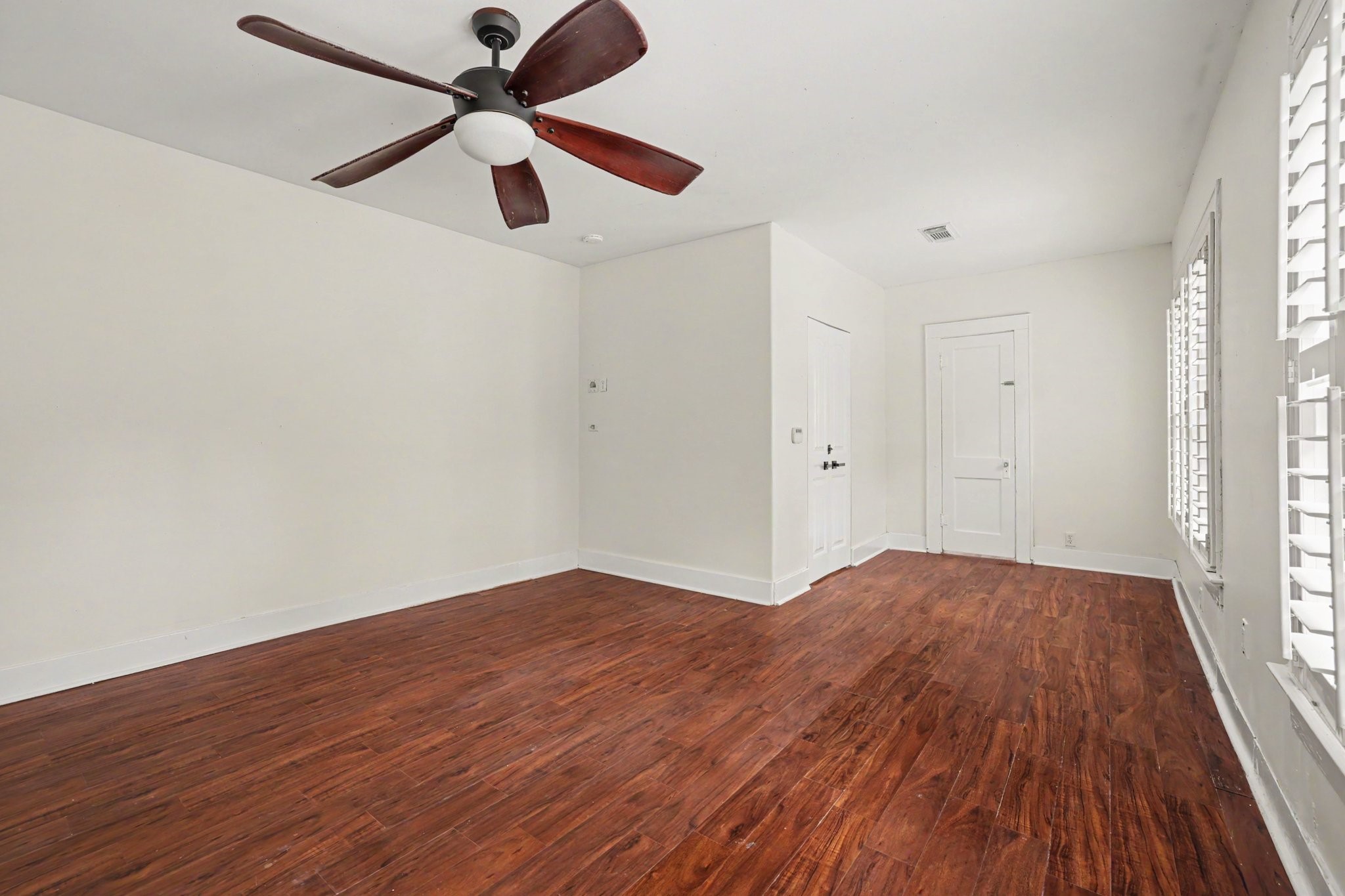 31730 Waller Tomball Road Waller, TX 77484 - Photo 25 of 50 Bright primary bedroom with rich wood flooring, a modern ceiling fan, and large windows with shutters.