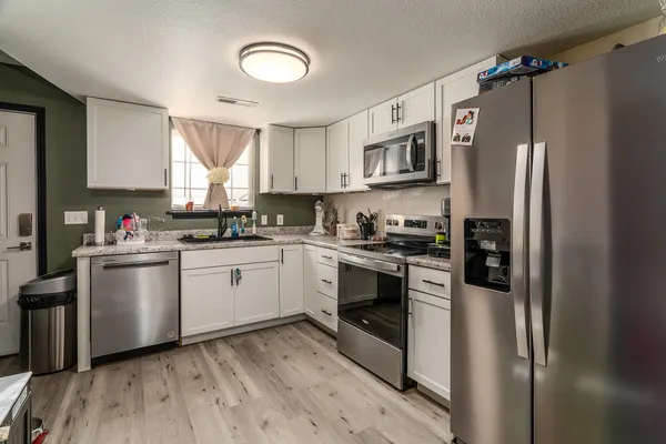 a kitchen with granite countertop a refrigerator stove and sink