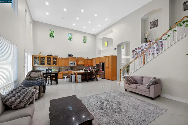 a open kitchen with stainless steel appliances granite countertop a stove top oven a dining table and chairs with the living room