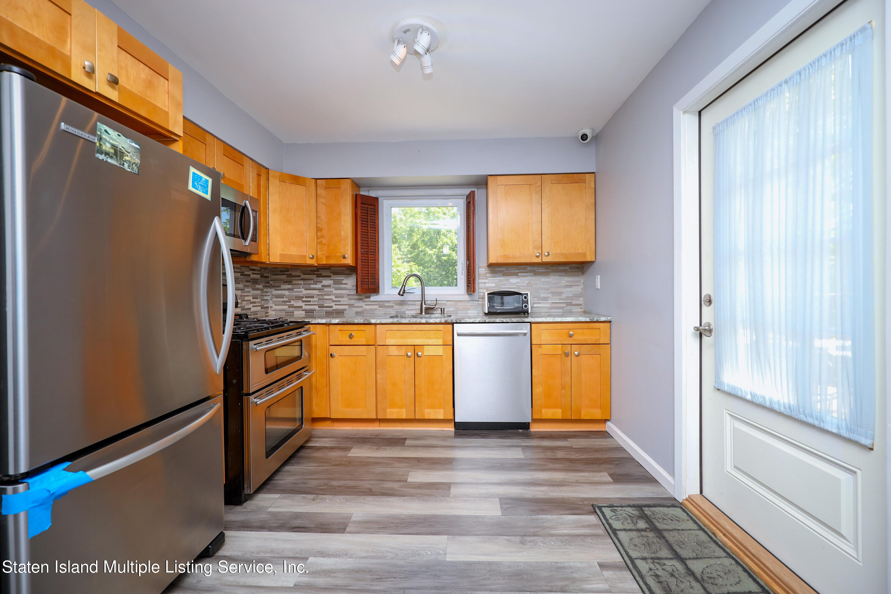 2209 Clove Road Staten Island, NY 10305 - Photo 13 of 38 a kitchen with granite countertop wooden floors stainless steel appliances and window