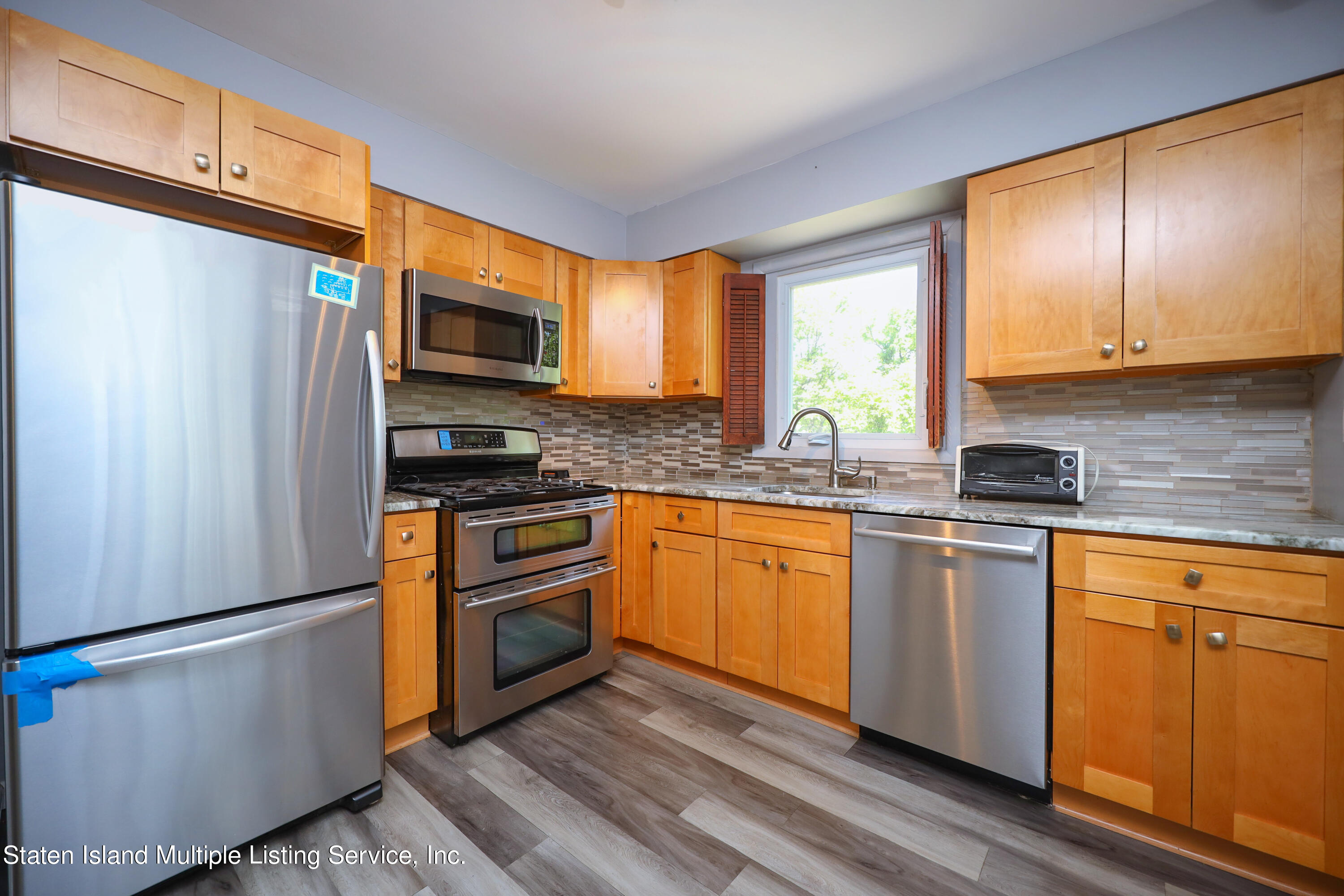 2209 Clove Road Staten Island, NY 10305 - Photo 14 of 38 a kitchen with stainless steel appliances granite countertop a refrigerator a microwave oven a sink dishwasher and wooden cabinets