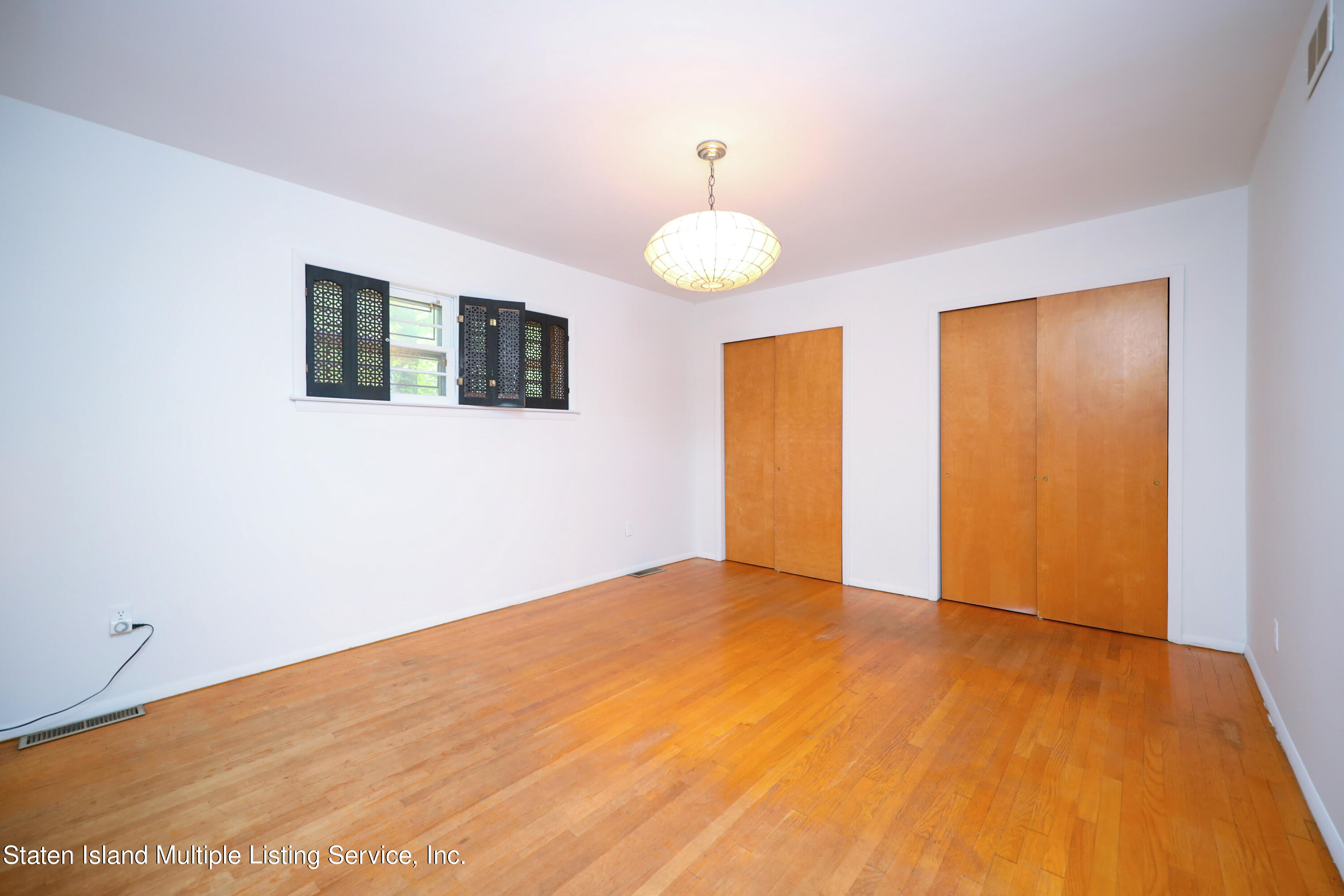 2209 Clove Road Staten Island, NY 10305 - Photo 9 of 38 a view of an empty room with wooden floor and a window