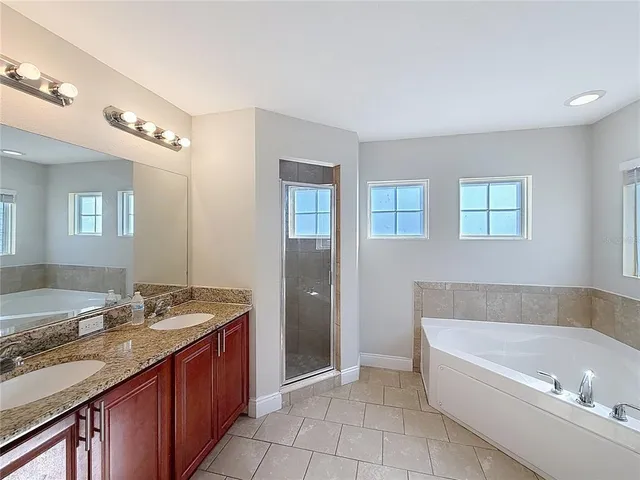 a bathroom with a granite countertop tub sink and mirror