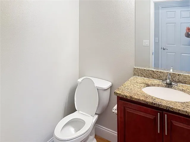 a bathroom with a granite countertop toilet sink and mirror