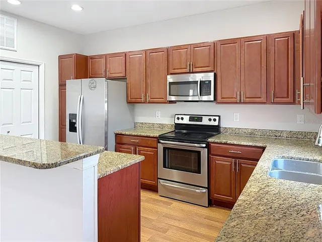 a kitchen with stainless steel appliances granite countertop a refrigerator stove top oven a sink and dishwasher