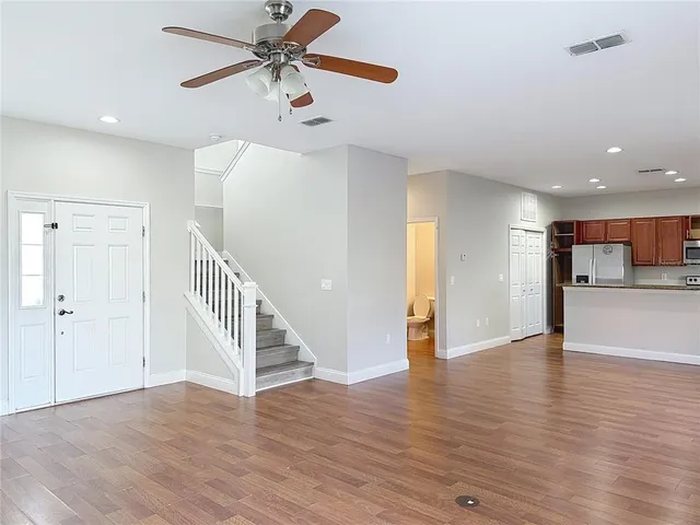 a view of an empty room with wooden floor and a ceiling fan