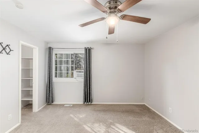 an empty room with windows and fan