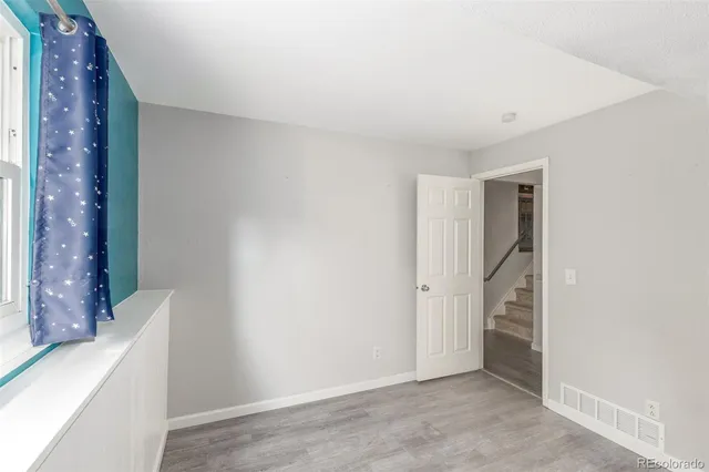 a view of an empty room with window and stairs