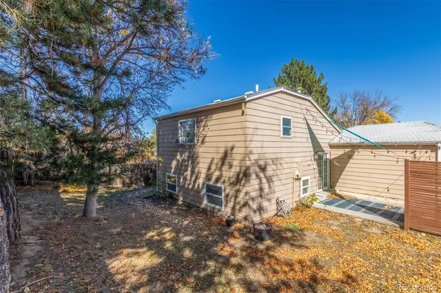 a view of a backyard with large trees and wooden fence