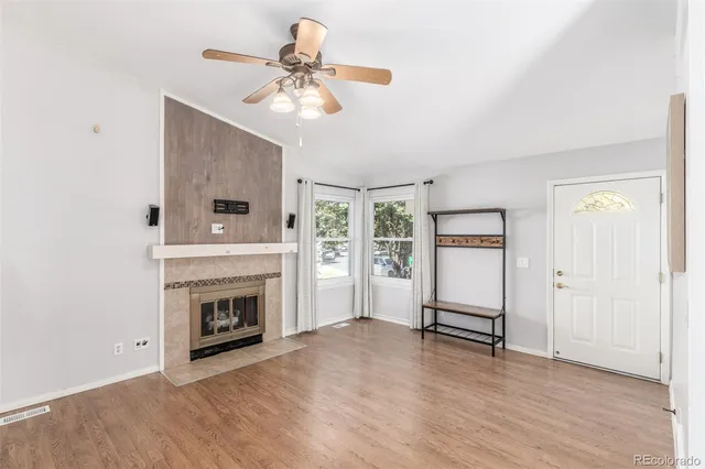a view of a livingroom with a fireplace a ceiling fan and wooden floor
