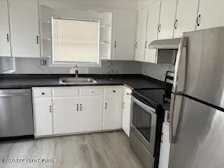 a kitchen with granite countertop white cabinets and stainless steel appliances