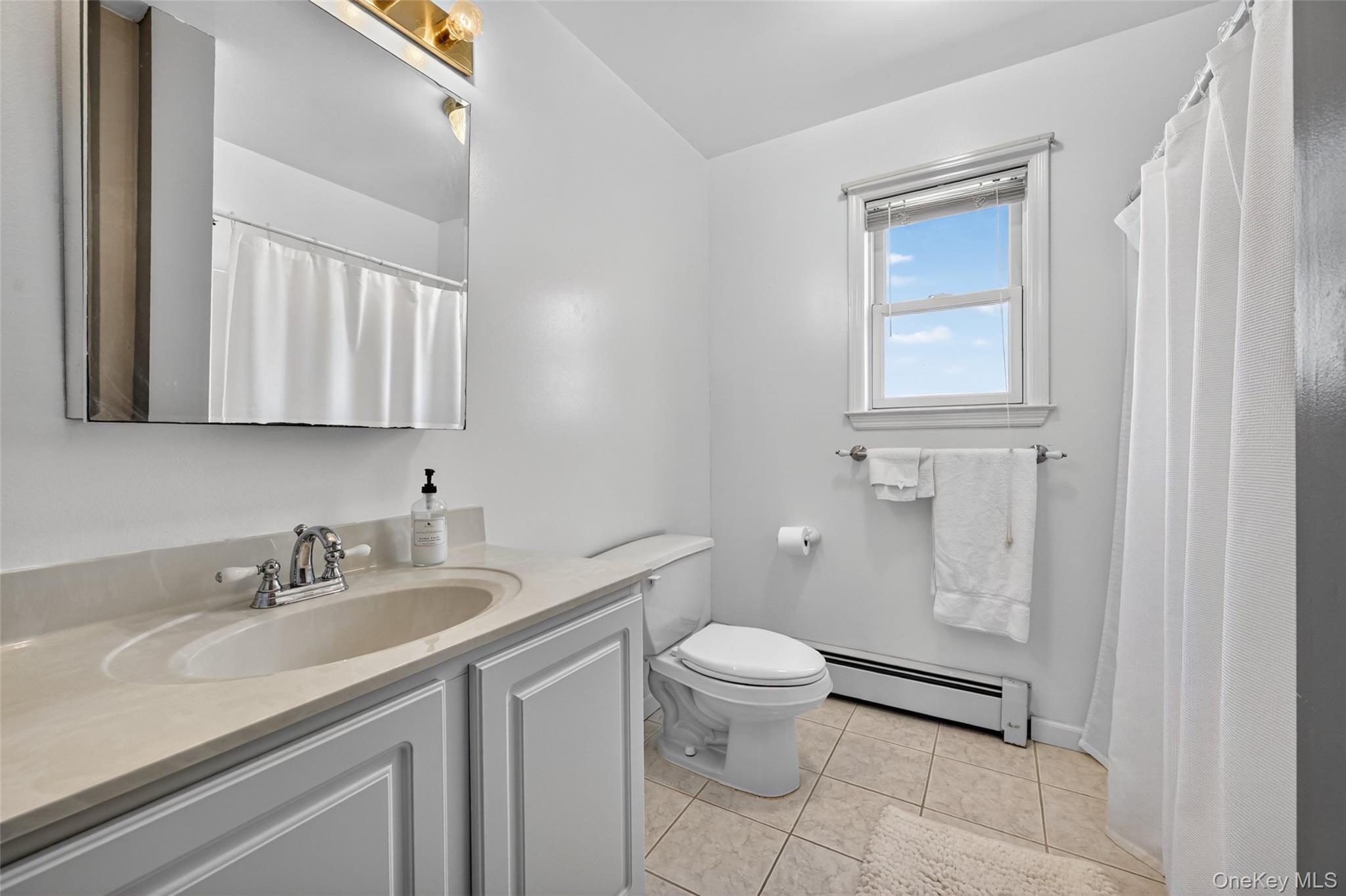 19 Bull Mine Road Chester, NY 10918 - Photo 26 of 42 Bathroom featuring a single vanity with a light-toned countertop, a window with blinds, a toilet, a full shower/tub combination with a curtain, and tile flooring