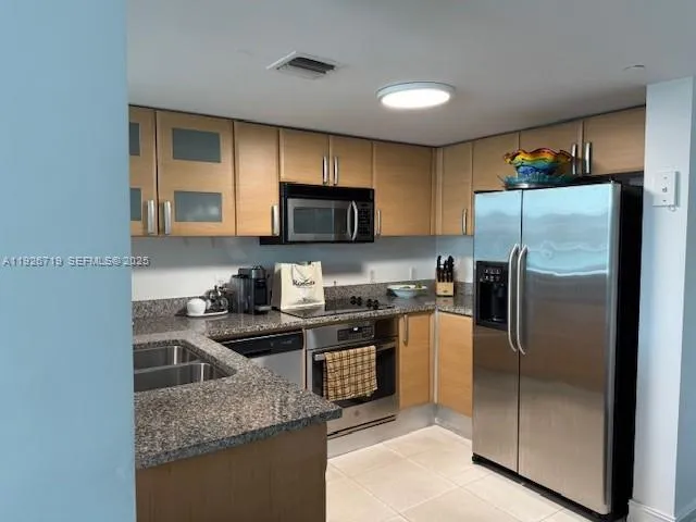 a kitchen with kitchen island granite countertop stainless steel appliances and a refrigerator