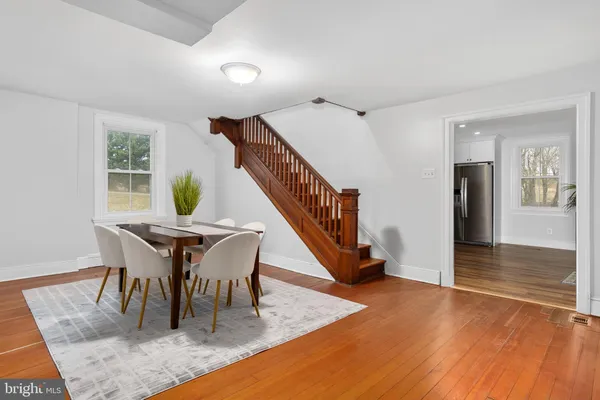 a kitchen with stainless steel appliances granite countertop a refrigerator a sink dishwasher a stove and a dining table with wooden floor