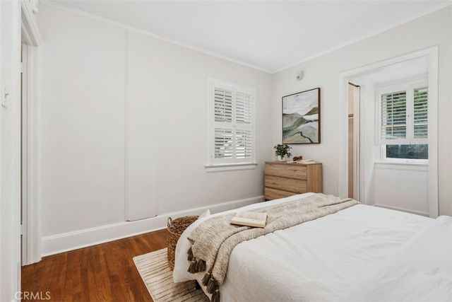 a bedroom with a bed and a window with wooden floor