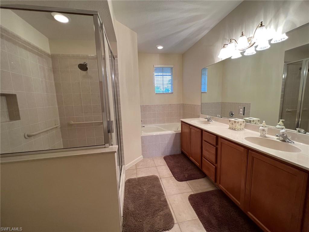 6821 Ascot Drive, Unit 202 Naples, FL 34113 - Photo 13 of 35 a bathroom with a double vanity sink a large mirror and shower