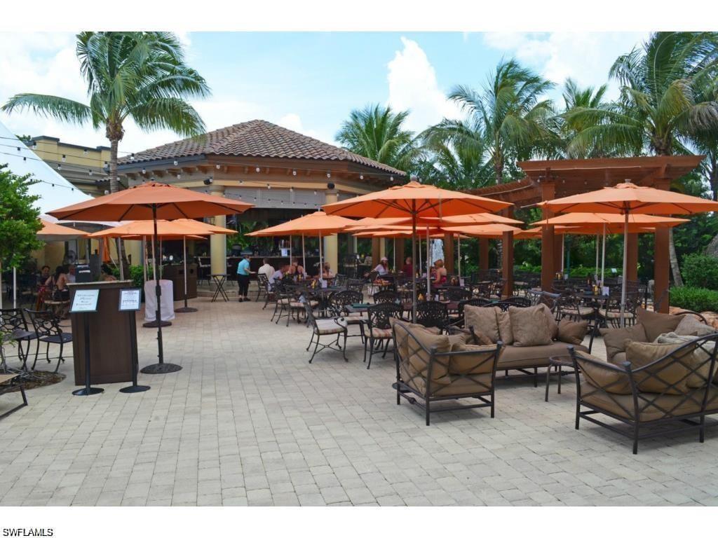 6821 Ascot Drive, Unit 202 Naples, FL 34113 - Photo 25 of 35 a patio with a table and chairs under an umbrella