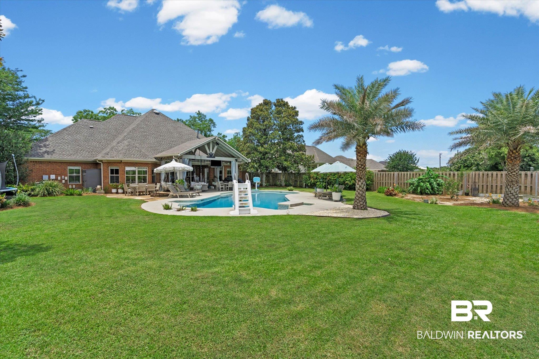24908 Bosbyshell Avenue Daphne, AL 36526 - Photo 31 of 49 Expansive backyard featuring a custom-shaped swimming pool with a slide, an outdoor covered patio, and a privacy fence