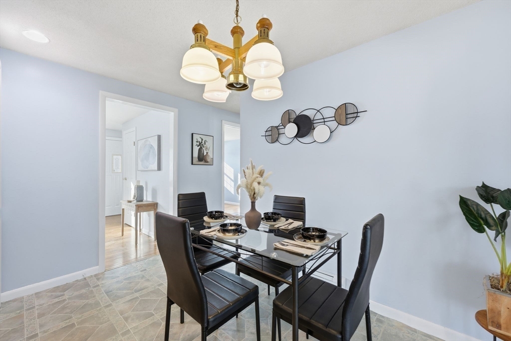 176 Silvin Road Chicopee, MA 01013 - Photo 12 of 32 a dining room with wooden floor a chandelier a wooden table and chairs