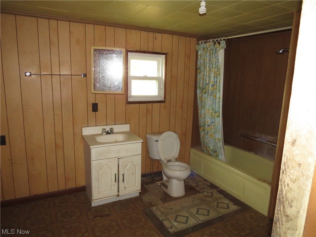 1054 Bergholz Road Southeast Bergholz, OH 43908 - Photo 6 of 11 Full bathroom with wood walls, toilet, shower / tub combo, and vanity