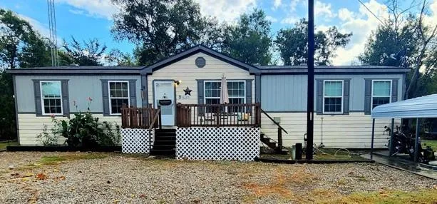 a view of a house with a small yard and a large tree