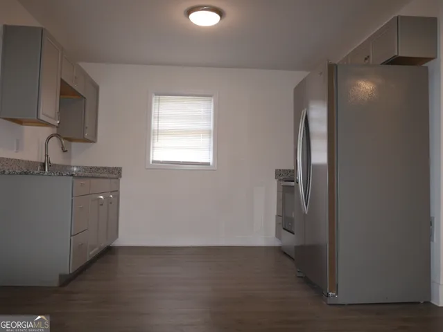 a kitchen with granite countertop a refrigerator and a sink
