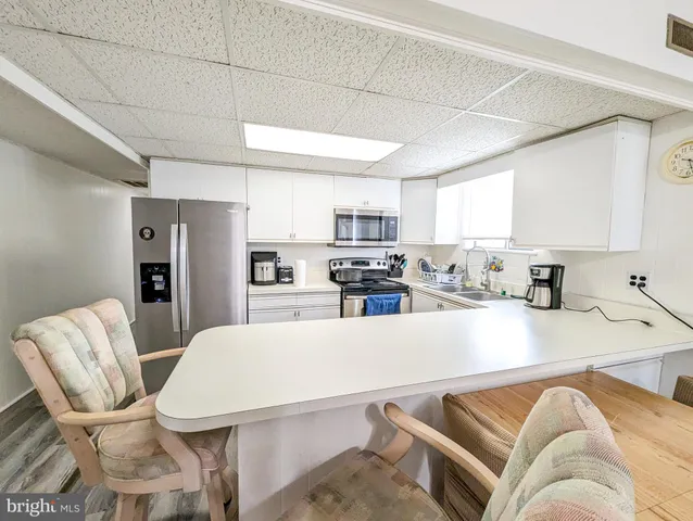 a living room with stainless steel appliances furniture a couch and a window