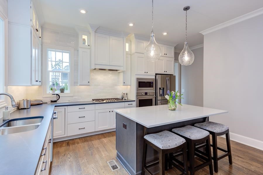 1017 Bradburn Drive Durham, NC 27713 - Photo 12 of 34 a kitchen with granite countertop a table chairs a sink dishwasher stove and cabinets with wooden floor