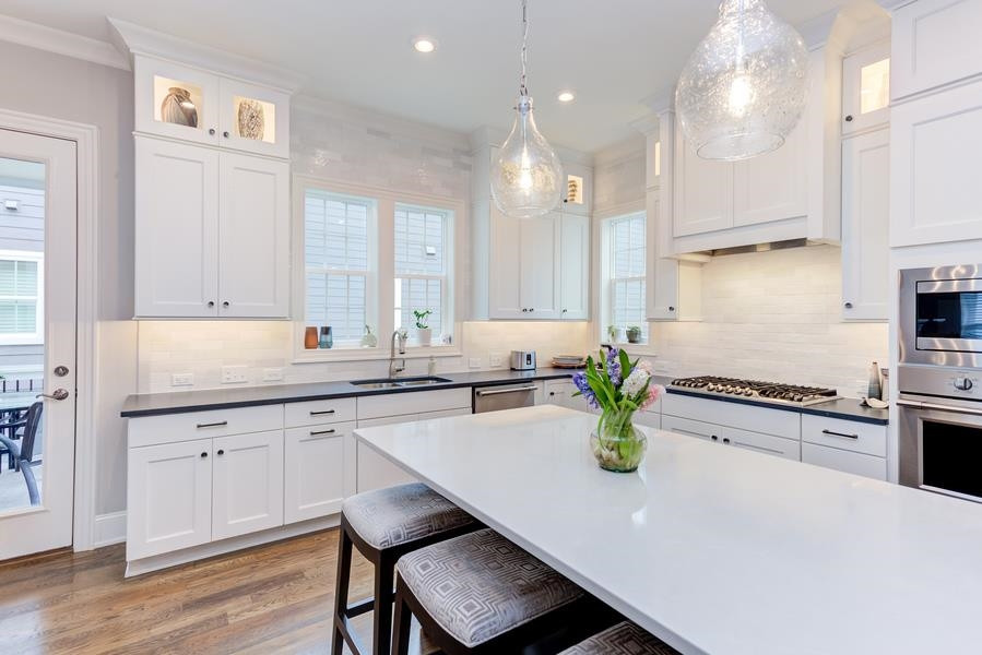 1017 Bradburn Drive Durham, NC 27713 - Photo 13 of 34 a kitchen with a sink a stove and chairs with wooden floor