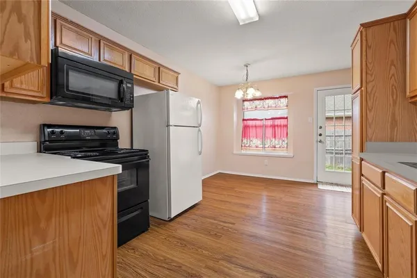 a view of kitchen with stainless steel appliances granite countertop a refrigerator a stove top oven a sink and dishwasher with wooden floor