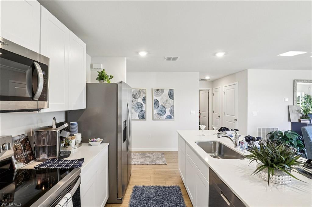 8022 Cedar Ky Way Lehigh Acres, FL 33971 - Photo 16 of 45 a kitchen with stainless steel appliances a sink stove top oven and cabinets
