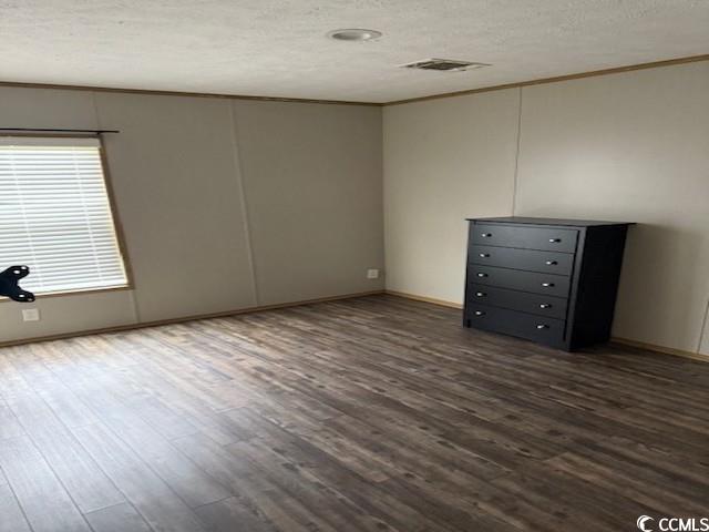 65 Clemmons Drive Tabor City, NC 28463 - Photo 19 of 29 Empty room with dark wood-style flooring, ornamental molding, a textured ceiling, and baseboards