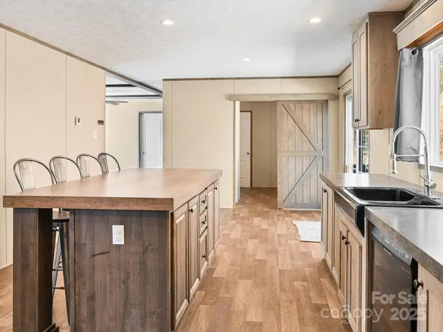 a hall with stainless steel appliances granite countertop a sink a stove and a refrigerator