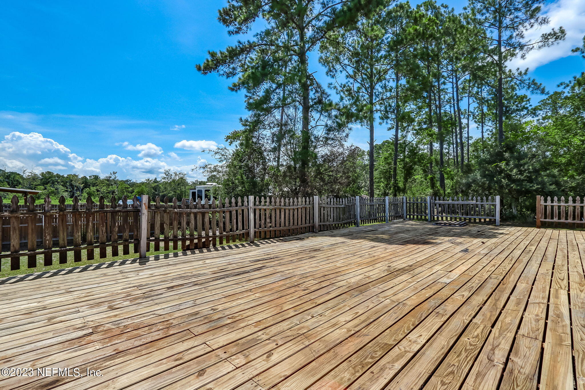 86105 Pages Dairy Road Yulee, FL 32097 - Photo 33 of 39 a view of deck with wooden floor and fence with a trees