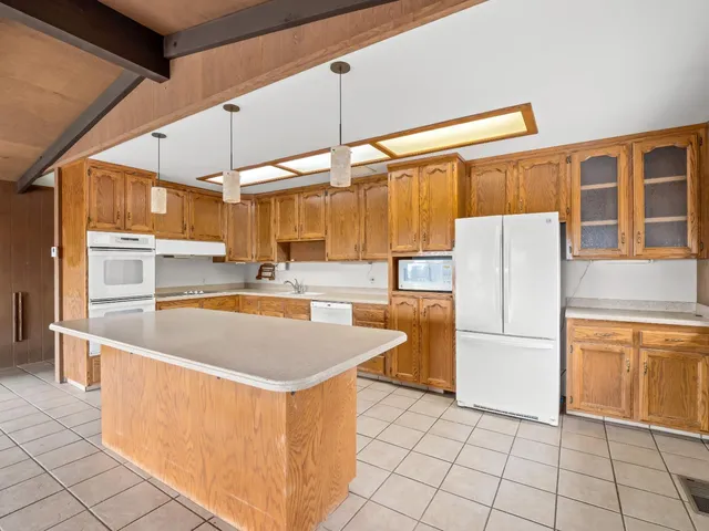 a kitchen with stainless steel appliances granite countertop a refrigerator a sink and white cabinets
