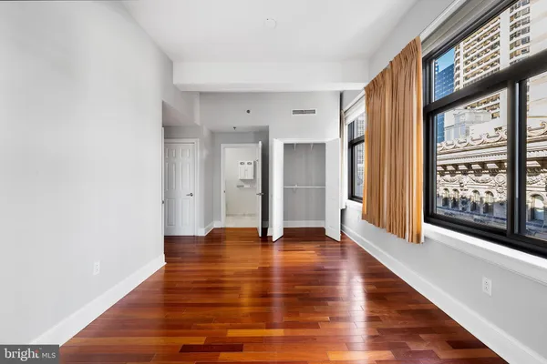 a view of an empty room with window and wooden floor