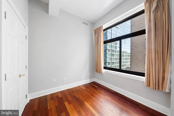 a view of an empty room with wooden floor and a window